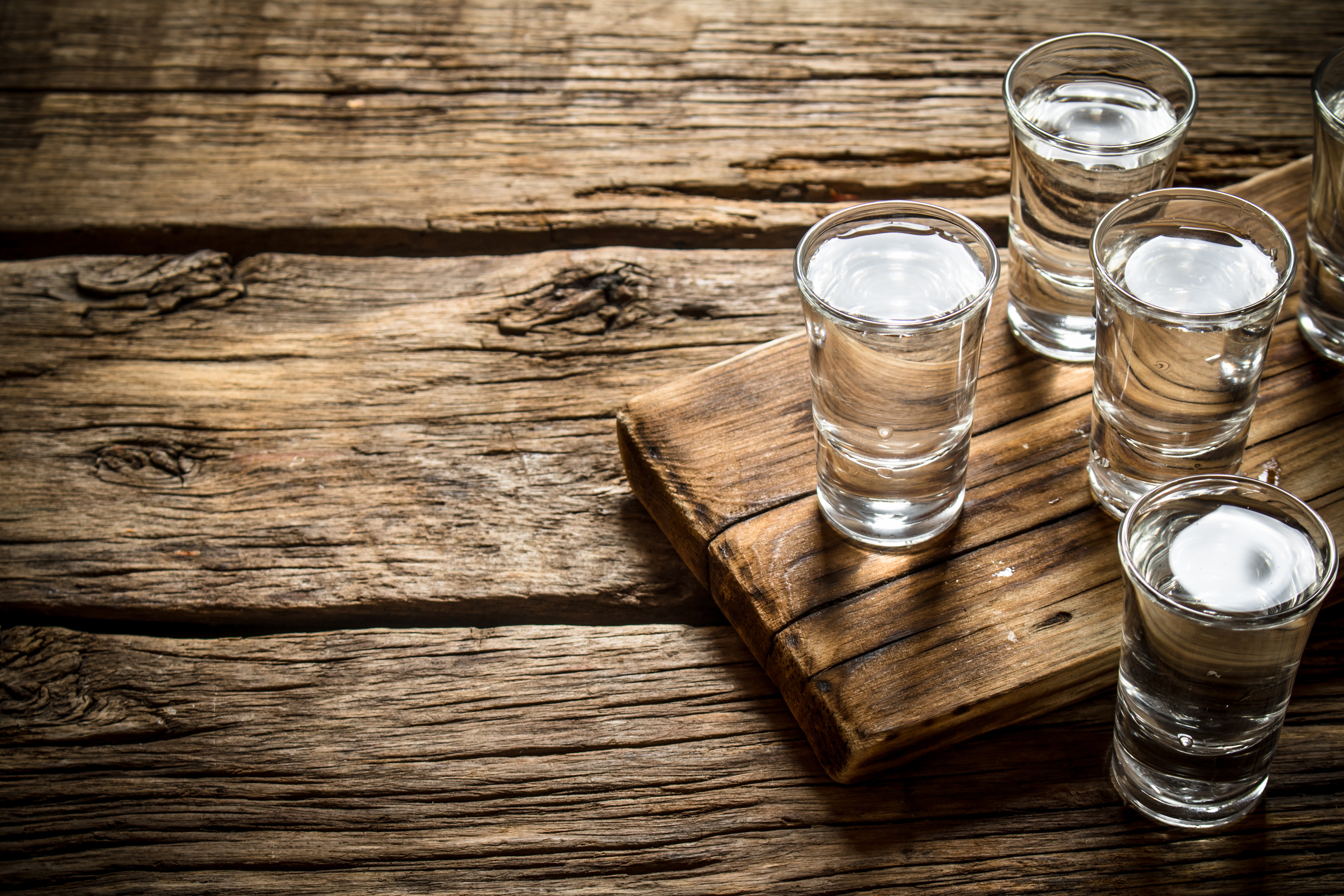 Glasses with vodka on the old Board. On wooden background.