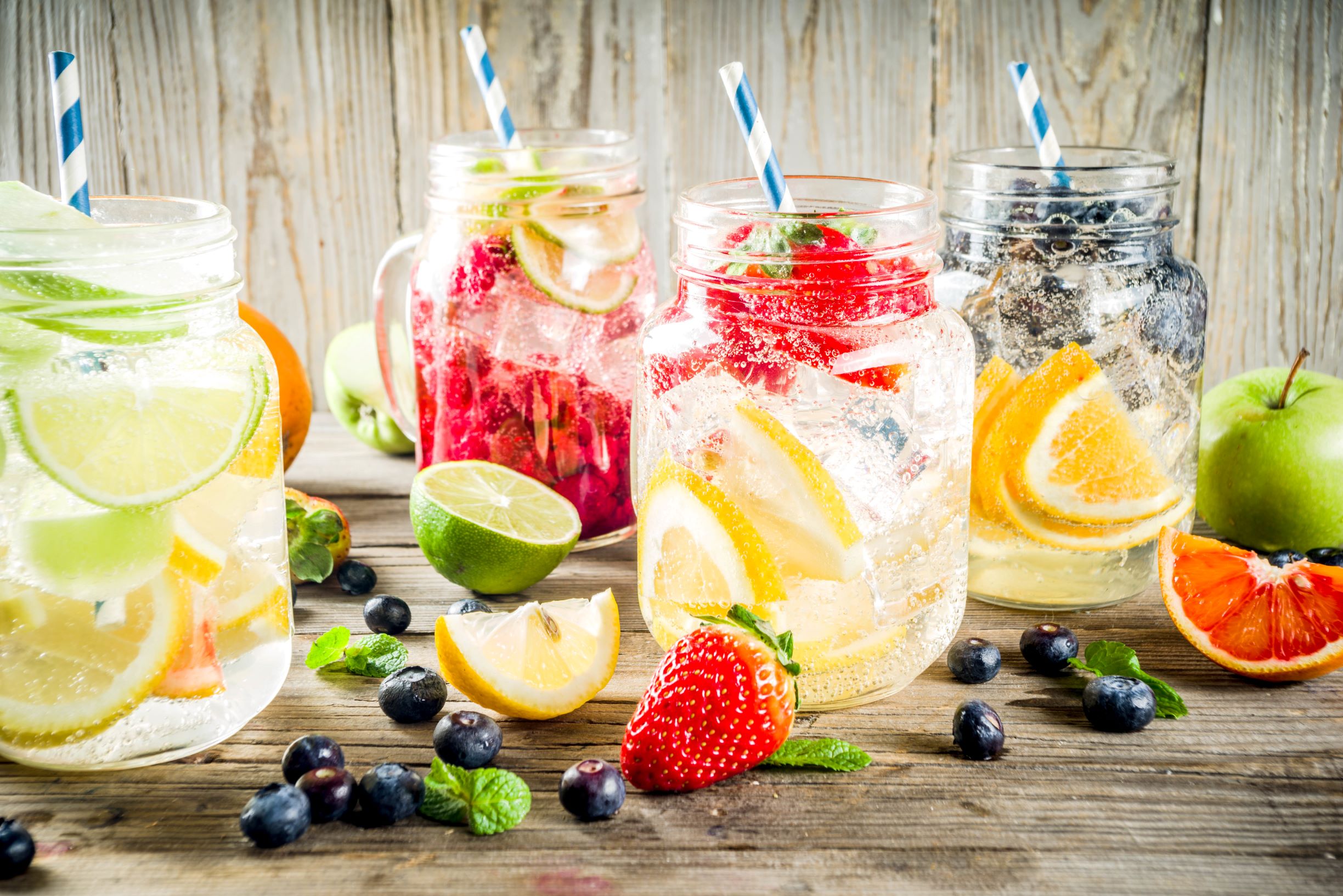 Fruit cocktails in mason jars with limes, lemons, oranges, strawberries and blueberries