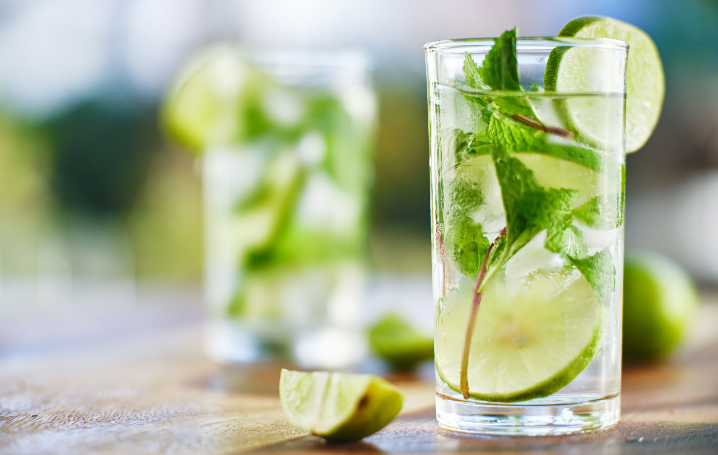 Lime and mint mojitos on a wooden table outside