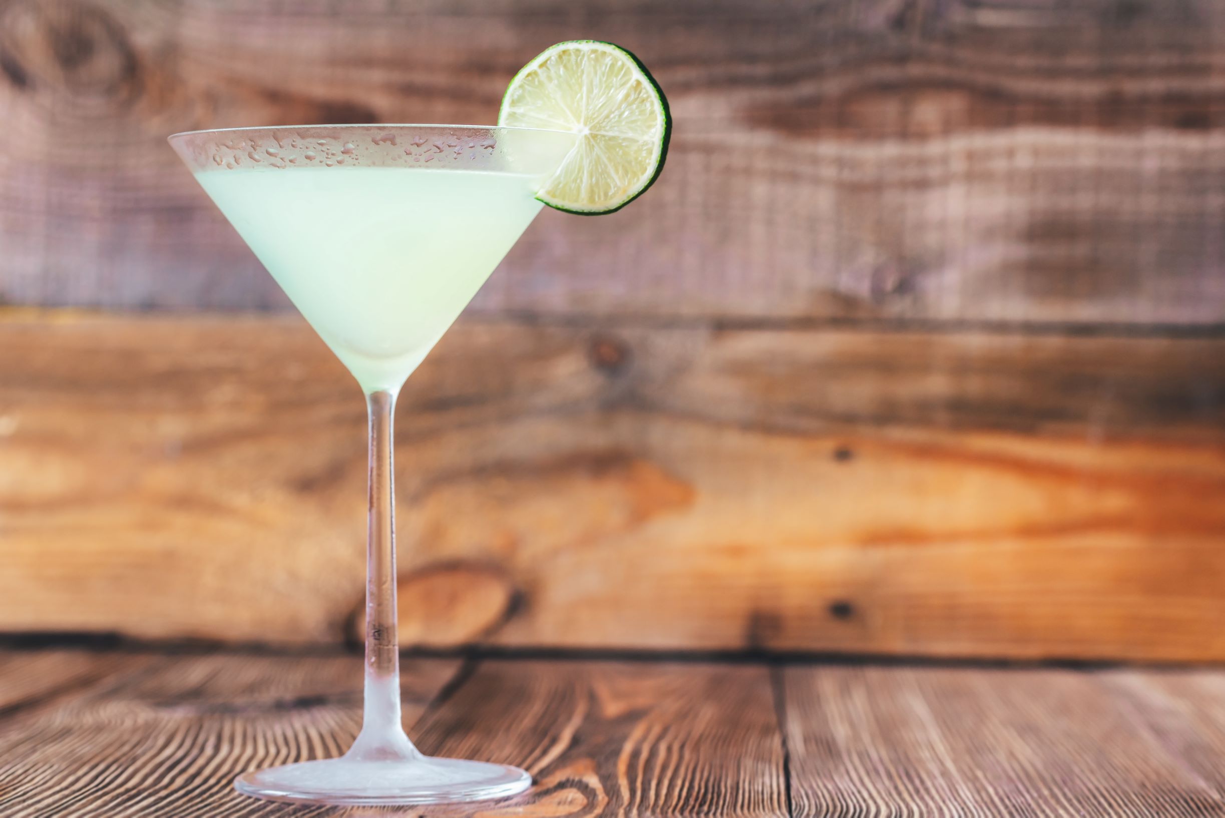 Classic daiquiri cocktail in a martini glass against wooden background