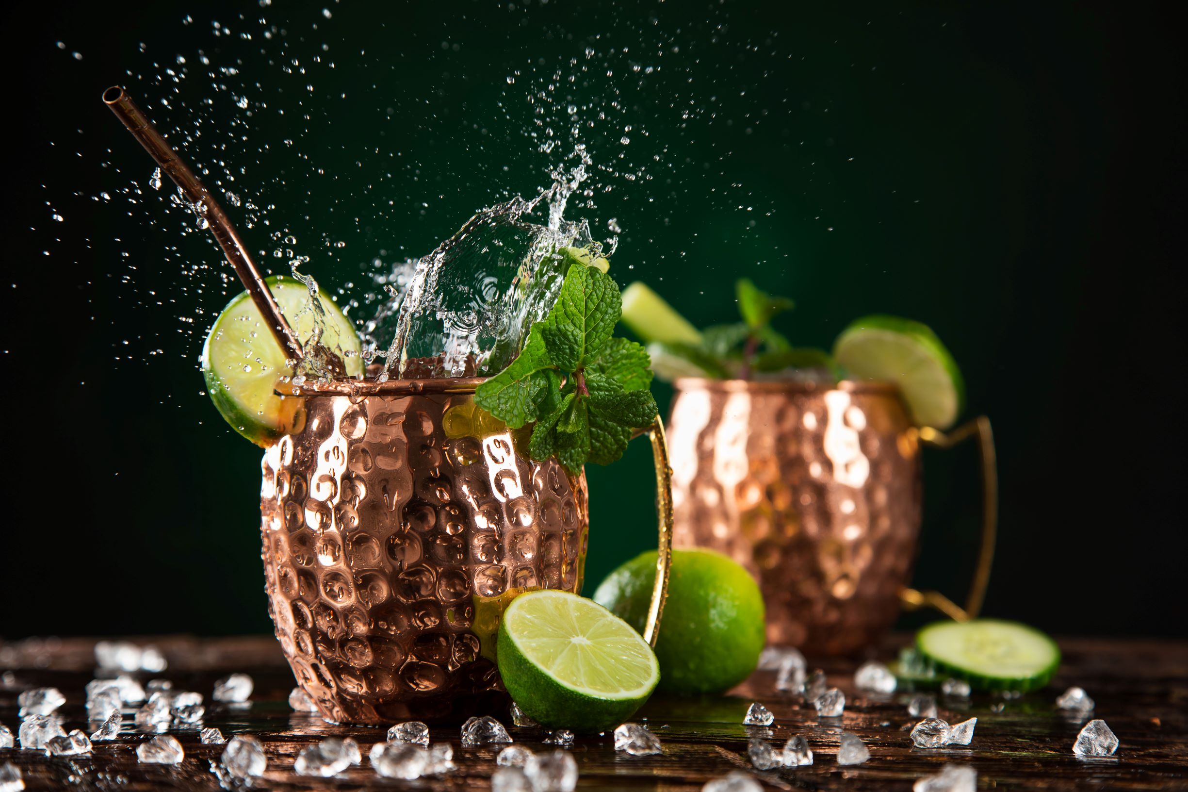 Two moscow mules with mint, ginger beer, limes and ice all in a copper mule ug