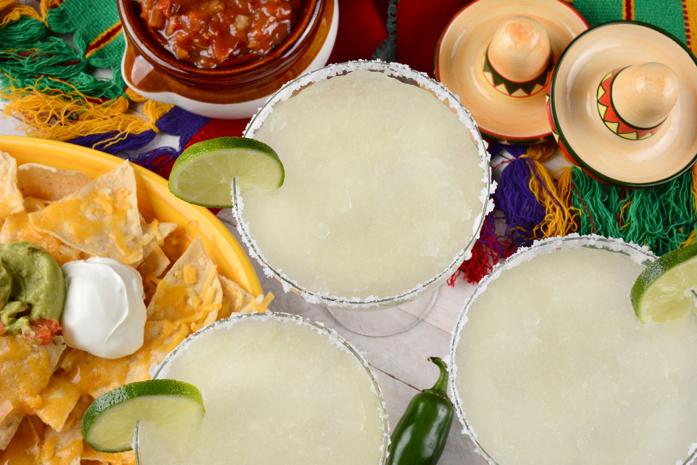Cinco de Mayo party with three margaritas on the rocks with lime wedges.
