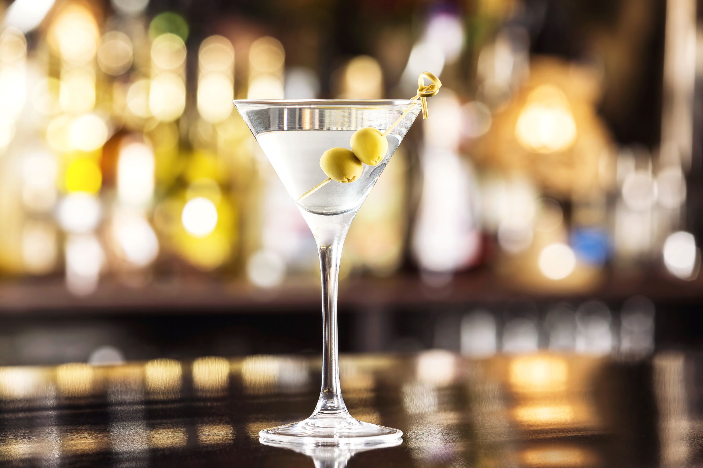 Martini glass with olives with a classy bar in the background