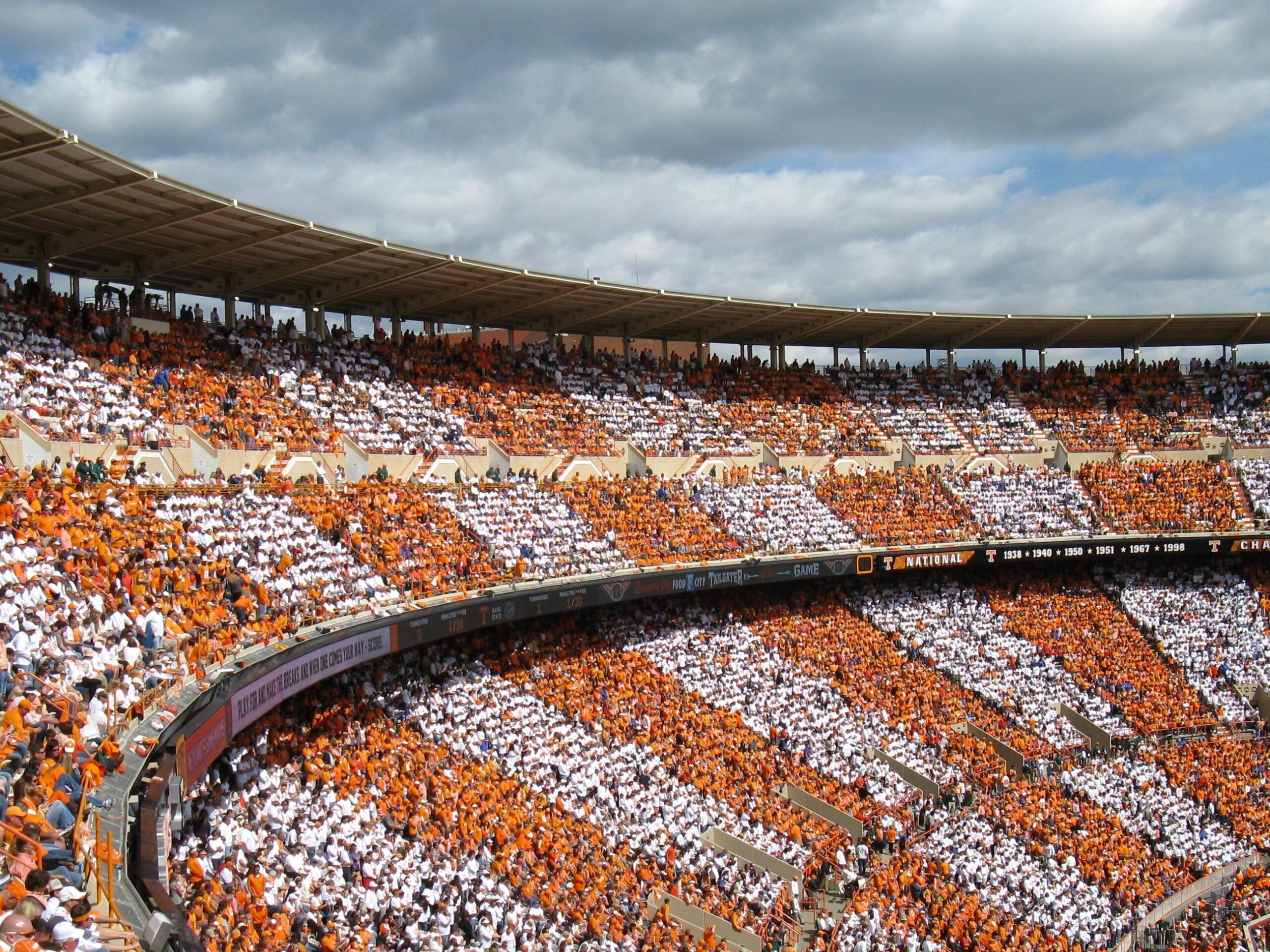 A football stadium filled with fans dressed in orange and white.