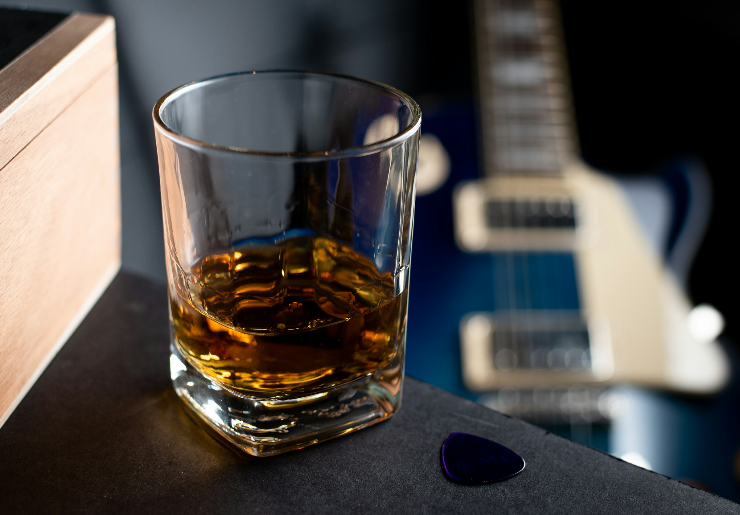 Glass of whiskey in front of an electric guitar